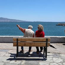 Ενα ζευγάρι ηλικιωμένων κάθεται σε παγκάκι μπροστά στη θάλασσα