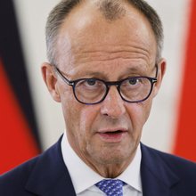 Φρίντριχ Μερτς μπροστά από γερμανικές σημαίες