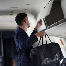 Επιβάτης βάζει την τσάντα του στα ντουλαπάκια του αεροπλάνου