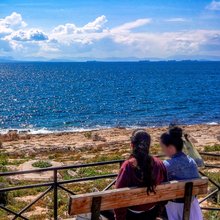 Δύο γυναίκες κάθονται σε παγκάκι και απολαμβάνουν τον ηλιόλουστο καιρό