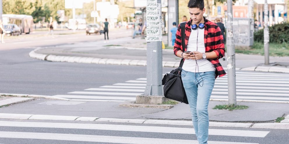 Πεζός διασχίζει διάβαση κρατώντας κινητό τηλέφωνο