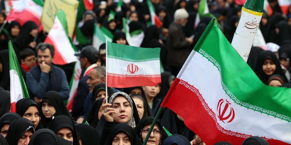 Ιρανοί, μεταξύ αυτών και γυναίκες, κρατούν σημαίες του Ιράν και στέκονται στο πλευρό του καθεστώτος 
