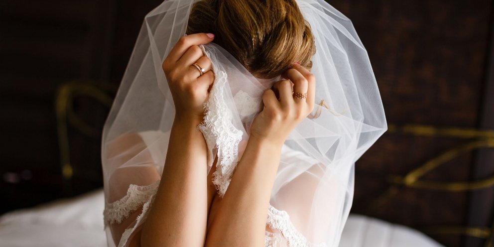 Νύφη καλύπτει το πρόσωπό της με τα χέρια και το πέπλο της - Shutterstock
