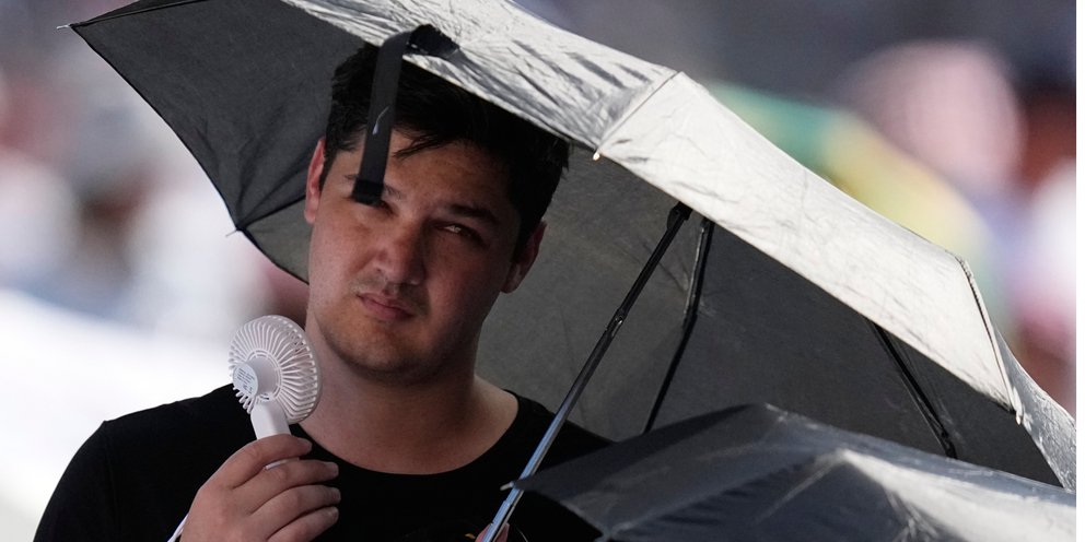 Ένας άνδρας δροσίζεται με ανεμιστηράκι στην πλατεία του Αγίου Πέτρου στο Βατικανό