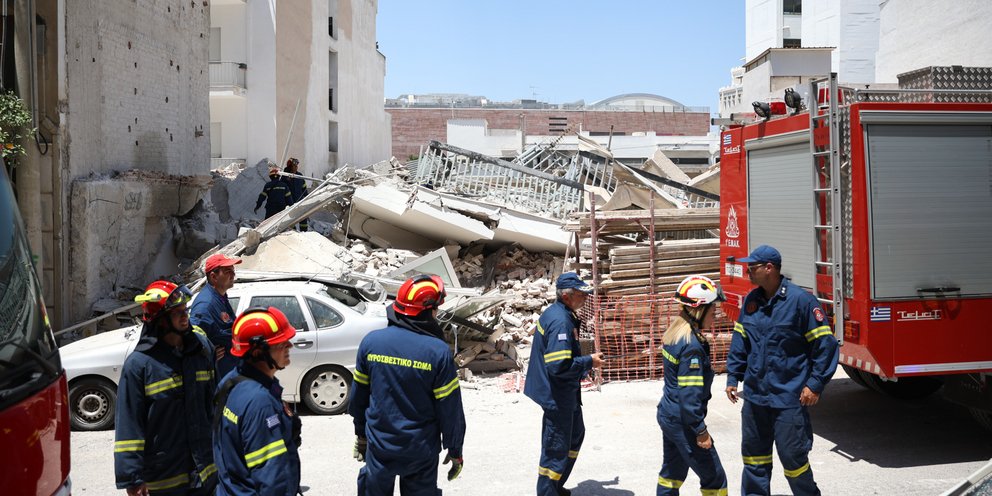 Πυροσβέστες με φόντο τα ερείπια της πολυκατοικίας που κατέρρευσε στα Πετράλωνα