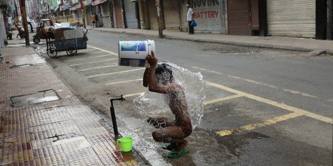 Ενας εργάτης στην Ινδία κάνει μπάνιο στη μέση του δρόμου 