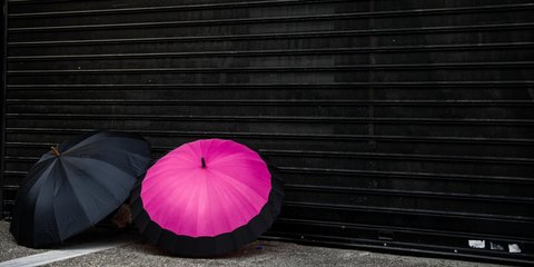 Ομπρέλες μπροστά σε κλειστά ρολά καταστημάτων