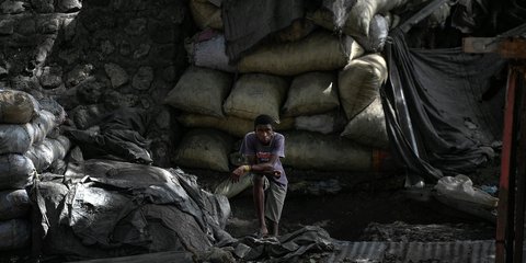 Νεαρός πωλητής μεταξύ τεράστιων σάκων με κάρβουνο στο Πορτ-ο-Πρενς, της Αϊτής, που δοκιμάζεται έπειτα από τη δολοφονία του προέδρου της χώρας, Ζοβενέλ Μοΐζ / Φωτογραφία: AP Photo/Matias Delacroix