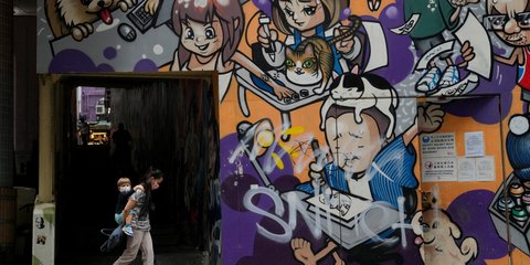 Μια μητέρα με το μωρό της περνά μπροστά από έναν απίθανο τοίχο με γκράφιτι στο Χονκ Κονγκ 