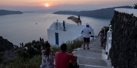 Ένα μαγικό ηλιοβασίλεμα στη Σαντορίνη με φόντο την καλντέρα, το απέραντο γαλάζιο και το λευκό των υπόσκαφων 