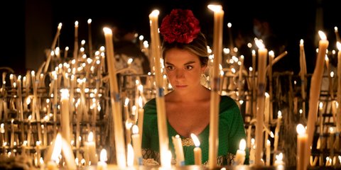 Ισπανίδα με φόρεμα φλαμένγκο μπροστά από κεριά σε ιερό ναό, στο πλαίσιο του φεστιβάλ la Romería del Rocío