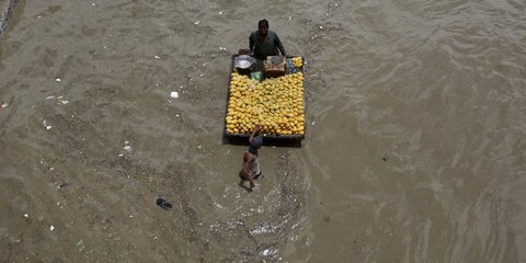 Ένας υπαίθριος πωλητής φρούτων, στο Καράτσι του Πακιστάν, φαίνεται... ανεπηρέαστος από το γεγονός ότι έχει πλημμυρίσει η πόλη του... / AP - Fareed Khan