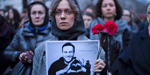 Μια γυναίκα κρατά λουλούδια και τη φωτογραφία του Ναβάλνι, έξω από τη Ρωσική πρεσβεία στο Βερολίνο 