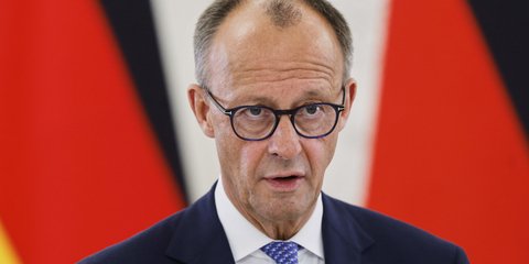 Φρίντριχ Μερτς μπροστά από γερμανικές σημαίες