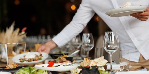 Σερβιτόρος τοποθετεί φαγητό στο τραπέζι