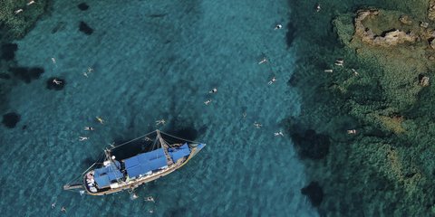 Λουόμενοι σε νερά του Ιουνίου πελάγους, δίπλα σε τουριστικό σκάφος