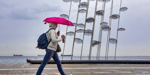Γυναίκα περπατά στη βροχή με ομπρέλα