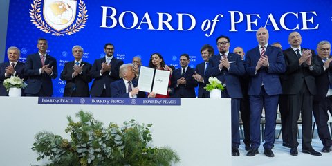 Ο Πρόεδρος Ντόναλντ Τραμπ, στο κέντρο, κρατάει ένα υπογεγραμμένο καταστατικό του Συμβουλίου Ειρήνης στο Νταβός