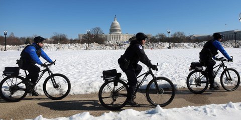 Αστυνομικοί περιπολούν με ποδήλατα έξω από το χιονισμένο Καπιτώλιο με ποδήλατα