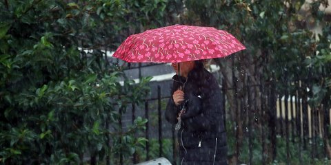 Γυναίκα κρατάει ομπρέλα για να προστατευτεί από τη βροχή 