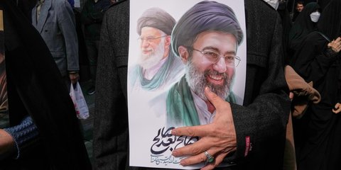 Οπαδός του ιρανικού καθεστώτος κρατά αφίσα με τον Αλί και τον Μοτζτάμπα Χαμενεΐ 