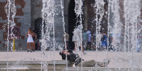 Μια γυναίκα δροσίζεται σε ένα σιντριβάνι στο κέντρο του Μιλάνου