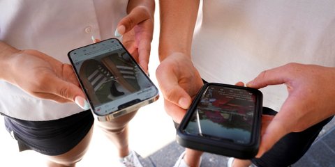 Έφηβοι χαζεύουν τα κινητά τηλέφωνά τους