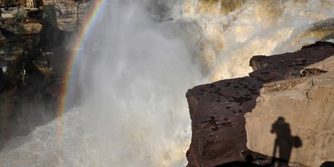 Μία... selfie με ουράνιο τόξο. Ο φωτογράφος που απαθανατίζει αυτό το υπέροχο στιγμιότυπο στους καταρράκτες Χούκου, στην Κίνα, εμφανίζεται ως σκιά στο βράχο. 