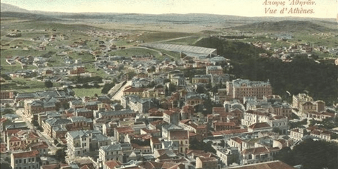 Aποψη της Αθήνας γύρω στο 1900. O τίτλος στα γαλλικά, όπως ήταν τότε η επίσημη δεύτερη  γλώσσα «Vue d'Athenes.   Η φωτογραφία ρετουσαρίστηκε σε έγχρωμη κι έτσι διακρίνουμε αριστερά από το Παναθηναϊκό στάδιο το καταπράσινο Παγκράτι.
