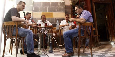 Σαν να μην συμβαίνει τίποτα: Στην Δαμασκό, στο παλιό κομμάτι της πόλης, ενώ μαίνεται ο εμφύλιος κάποιοι άνδρες καπνίζουν ναργιλέ σε καφενείο.