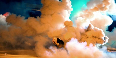 Σκηνικό πολέμου στο Μιζούρι των ΗΠΑ. Διαδηλωτής που διαμαρτύρεται για τον θάνατο από πυρά αστυνομικού του αφροαμερικανού Μάικλ Μπράουν, προσπαθεί να προστατευθεί από τα δακρυγόνα και τα χημικά που πέφτουν βροχή δίπλα του. Το στιγμιότυπο απαθανατίστηκε από