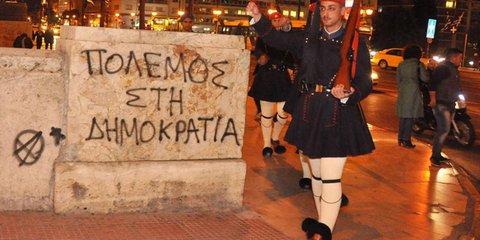 Aλλαγή της Προεδρικής Φρουράς χθες βράδυ, μπροστά από το φρεσκογραμμένο σύνθημα «Πόλεμος στη Δημοκρατία», στον περίβολο της Βουλής. Φωτογραφία του Γιάννη Μπαρδόπουλου