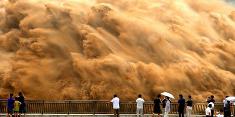 Toυρίστες παρακολουθούν το «ξέσπασμα» του Κίτρινου Ποταμού στην Κίνα. Παρότι μοιάζει με την εικόνα μιας μεγάλης καταστροφής, στην πραγματικότητα αποτελεί το σκηνικό μιας πολύ προσεκτικά σχεδιασμένης διαδικασίας, με σκοπό να καθαριστούν τα φράγματα του ποτ