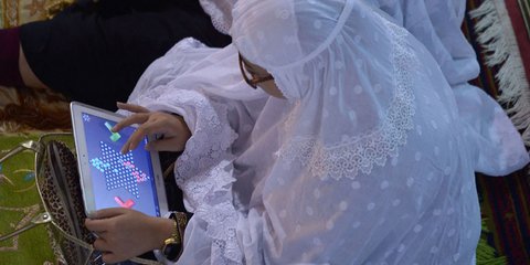 Ινδονήσια πιστή μουλουλμάνα παρίσταται στην πρώτη νύχτα του Ραμαζανίου και παίζει παιχνίδια στην ταμπλέτα της για να περάσει η ώρα κατά τη διάρκεια του κηρύγματος στο τζαμί Ιστιγκλάλ στην Τζακάρτα 