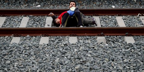 Το πρόσωπο της απελπισίας: Μετανάστης με το παιδί του ξαπλωμένοι στις ράγες στον σταθμό Λαρίσης -Φωτογραφία: AP Photo/Thanassis Stavrakis