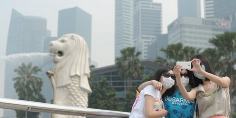 Οι τουρίστες στην Σιγκαπούρη με μάσκες και γυαλιά ηλίου φωτογραφίζονται με φόντο την ατμοσφαιρική ρύπανση που έχει εκτοξευθεί σε ύψη ρεκόρ για τρίτη συνεχόμενη ημέρα 