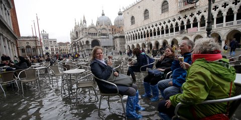 Τουρίστες αψηφούν τις πλημμύρες στη Βενετία και απολαμβάνουν το παγωτό τους στην πλατεία Αγίου Μάρκου -Φωτογραφία: AP Photo/Luca Bruno