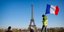 Ανδρας κρατά την σημαία της Γαλλίας μπροστά από το πύργο του Άιφελ