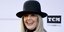 Η Ντάιαν Κίτον με λευκό πανωφόρι και μαύρο καπέλο χαμογελάει