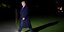 Ο Ντόναλντ Τραμπ περπατά με το παλτό του σε κήπο μέσα στο βράδυ