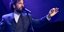 O Kωστής Μαραβέγιας με κοστούμι σε συναυλία μπροστά από το μικρόφωνο