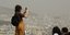 Μια τουρίστρια βγάζει φωτογραφία από τον Λυκαβηττό, σε ημέρα υψηλών συγκεντρώσεων αφρικανικής σκόνης