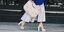 Γυναίκα περπατάει κρατώντας τσάντα, φοράει λευκές πλατφόρμες και μπλε σακάκι