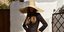 Γυναίκα με μαύρο φόρεμα και ψάθινο καπέλο