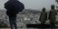 Δυο παιδιά με έναν ενήλικα κοιτάζουν τη βροχή από τον Λυκαβηττό, με θέα την Ακρόπολη