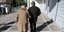 Ζευγάρι ηλικιωμένων περπατά, αγκαζέ, στην πλατεία Κλαυθμώνος