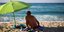 Ενας άνδρας με ομπρέλα για τον ήλιο σε παραλία της Ικαρίας