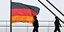 Δυο άνθρωποι περνούν μπροστά από μια γερμανική σημαία στο κτίριο της γερμανικής κυβέρνησης
