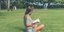 Γυναίκα διαβάζει βιβλίο καθισμένη στο γρασίδι