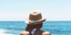 Γυναίκα πλάτη φοράει ψάθινο καπέλο και κοιτάζει τη θάλασσα